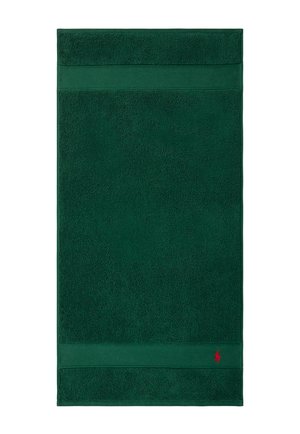 Asciugamano rettangolare verde scuro con fasce testurizzate vicino ai bordi e un piccolo logo ricamato rosso nell'angolo in basso a destra.