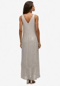 Silberner Pailletten-Kleid mit V-Ausschnitt. Lange, fließende Form und strukturierter Stoff. Besitzt einen subtilen Glanz, geeignet für formelle Anlässe.