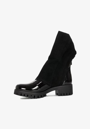 Czarne botki sięgające kostki, z połyskującym lakierowanym noskiem oraz miękką zamszową cholewką z charakterystycznym złożonym kołnierzem, teksturowaną gumową podeszwą.