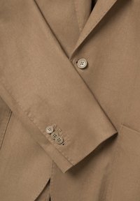 Blazer in cotone marrone con rever a punte, dettaglio dei polsini a quattro bottoni e tessuto texture con tasca laterale.