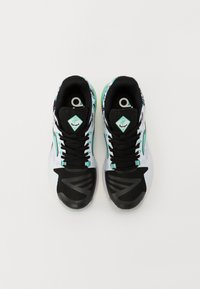 Zapatillas deportivas en blanco y negro con acentos en turquesa, parte superior de malla, patrones distintos y suelas de goma. Los cordones son negros y planos.