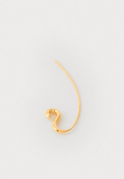 Złote metalowe kolczyki w kształcie stylizowanej krzywej S z gładką powierzchnią, z cienkim, wydłużonym prętem skierowanym ku górze.