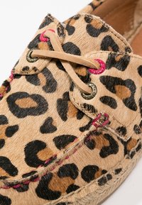 Louisdrupp print moccasin-stijl schoen van getextureerd dierenbont met een beige basis, roze stiksels en goudkleurige veterogen.