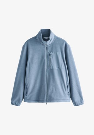 Svijetloplavi flis jakna s potpunim prednjim patentnim zatvaračem, visokim ovratnikom, prsnom džepom na patentni zatvarač s tkaninom za izvlačenje i dva bočna džepa.