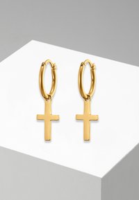 Orecchini a cerchio in oro con una superficie liscia, caratterizzati da un pendente a croce verticale. Il design è semplice e minimalista.