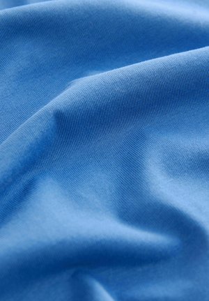 Tessuto di cotone blu chiaro con una texture liscia, caratterizzato da un delicato rigaggio e morbide pieghe, che mostrano flessibilità e sofficezza.