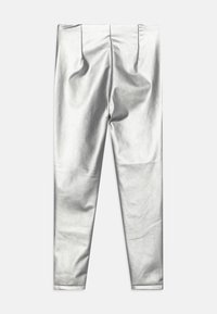 Leggings metálicos prateados com uma textura suave e design justo; apresenta pregas na cintura e aberturas de perna estreitas.