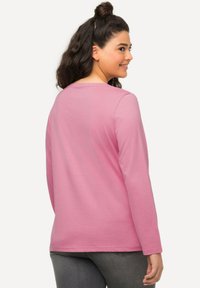 Pink long-sleeve shirt with a round neckline, made of soft cotton fabric, drapes comfortably, and features a relaxed fit.