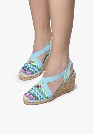 Wedge espadrilles with a light blue fabric upper, colorful zigzag embroidery, and a jute-wrapped wedge heel. Adjustable elastic straps.