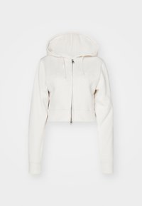 Hoodie bianco tagliato con zip frontale, maniche lunghe e cappuccio con lacci. Presenta un logo impresso sul petto. Materiale e texture morbidi.