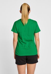 Grøn bomulds t-shirt med klassisk rund halsudskæring, korte ærmer og lige kant, parret med sorte shorts. Glat tekstur, afslappet design.
