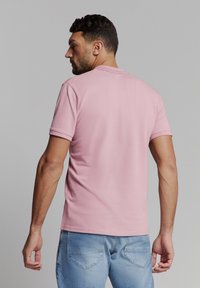 Roze katoenen t-shirt met korte mouwen, geribbelde ronde hals en een relaxte pasvorm, gecombineerd met lichtblauwe spijkerbroeken. Minimalistisch ontwerp.