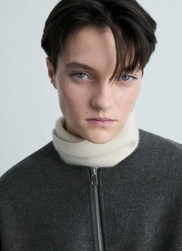 Giacca grigia in lana con zip frontale e alto colletto a dolcevita color crema. Texture liscia, design minimale e sottile contrasto tra i colori.