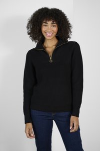 Pull en tricot noir avec un zip quart, présentant une texture côtelée et une fermeture éclair dorée. Associé à un jean bleu foncé.