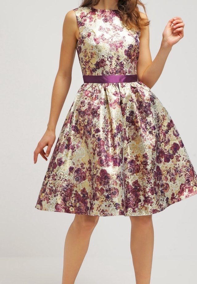 Hihaton polvipituinen mekko, jossa on violetti, kulta ja kerma kukkakuvio sekä kiiltävä violetti vyötärönauha. Malli kuvattuna hartioista polviin.