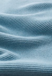 Lichtblauwe geribbelde stof met een getextureerd oppervlak, met parallelle lijnen en verschillende blauwtinten voor diepte. Glad en flexibel.