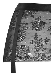 Czarna koronkowa spódnica z kwiatowymi wzorami i przezroczystym designem. Posiada solidny czarny pas i ozdobne wykończenie u dołu.