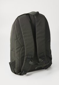 Mochila de tecido preto com alças acolchoadas e ajustáveis, uma textura suave e um design minimalista com costuras reforçadas e detalhes em fita.