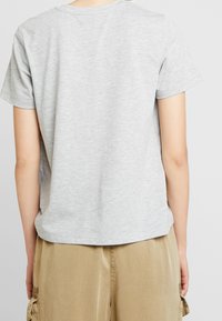 Lys grå t-shirt med korte ærmer i blødt bomuldsstoff. Har rund halsudskæring og en afslappet pasform med en let afrundet kant.