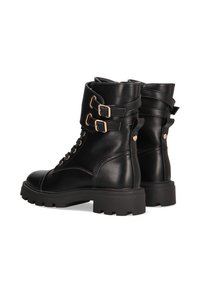 Botas de cuero negro hasta el tobillo con punta redondeada, cordones en la parte frontal, correas laterales dobles y herrajes en tono dorado. Suela de goma gruesa con agarre texturizado.