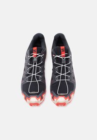 Μαύρα αθλητικά παπούτσια με κόκκινες λεπτομέρειες, υφασμένα πέλματα και ελαστικά κορδόνια. Διαθέτουν ενισχυμένη μύτη και μαλακό εσωτερικό.