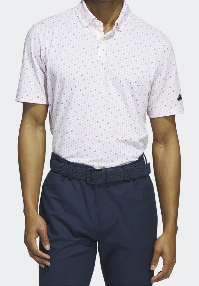 Kortærmet polo-shirt i lys pink med blåt blomsterprint. Kombineret med mørk navy bukser og et struktureret navy bælte.