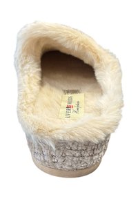 Beige, harige slipper met een zachte, plush binnenkant en een geprofileerde buitenkant. Kenmerkt zich door een vlakke, ronde zool en een merklabel aan de binnenkant.