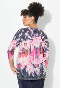 Färgglad tröja med en blandning av rosa, lila och svarta abstrakta mönster, med trekvartsärmar och en avslappnad passform.