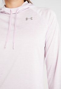 Helles rosa, langärmliges Oberteil mit Kapuze aus einem glatten, leichten Stoff. Verfügt über ein kleines graues Under Armour-Logo auf der Brust und Kordeln.