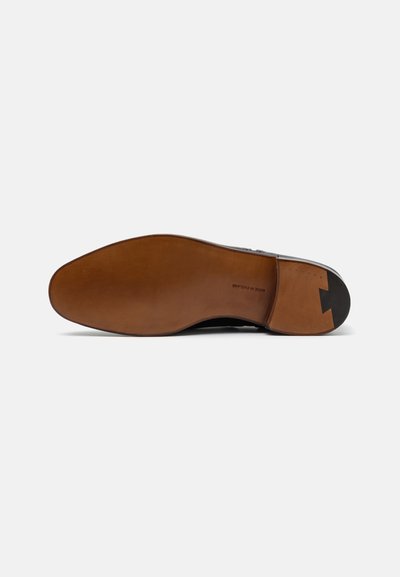 Scarpa in pelle nera con una finitura liscia, caratterizzata da una suola in pelle marrone. La suola presenta un motivo distintivo e una forma affusolata nella punta.