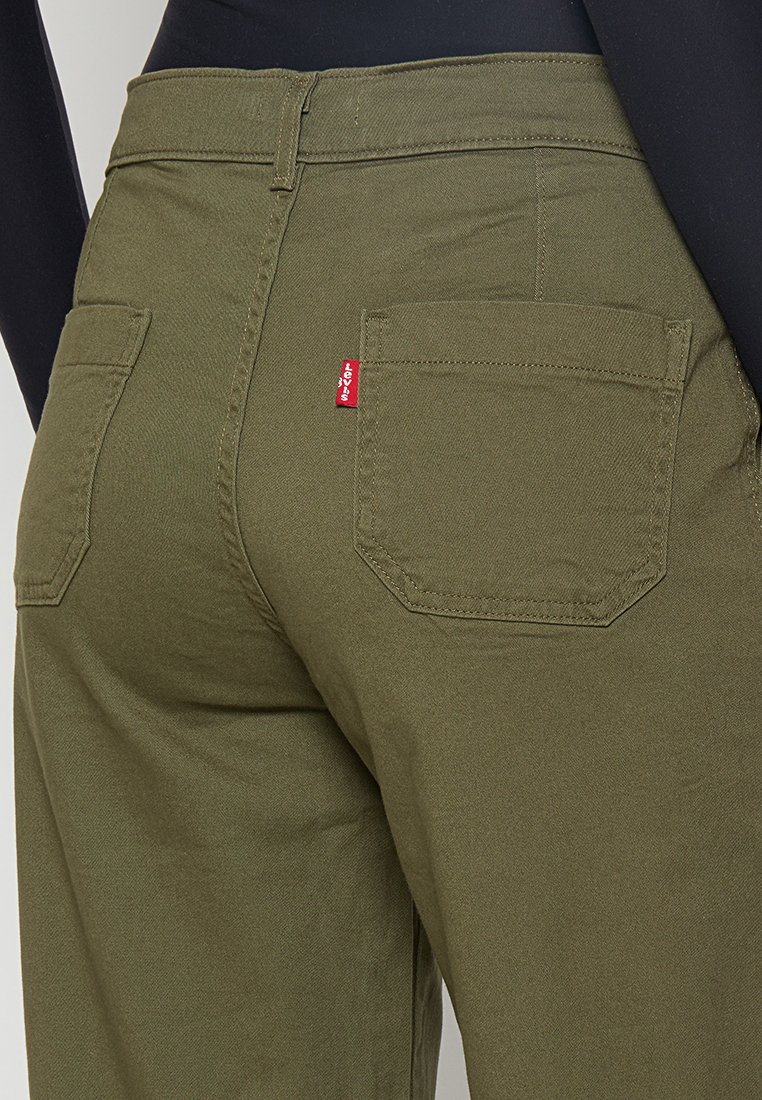 Pantalons vert olive avec une texture lisse, dotés de deux poches arrière et d'une étiquette rouge Levi's sur la poche droite.