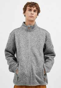 Jachetă gri cu fermoar, realizată dintr-un material fleece texturat. Dispune de un guler înalt, două buzunare laterale și un accent din lemn pe tragerea fermoarului.