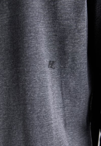 T-shirt cinza escuro feita de um tecido suave e texturado, apresentando uma impressão de logotipo sutil e um design simples, sem padrões ou detalhes.