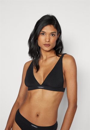 Black wireless bralette with a V-neck design, made of soft fabric; features wide straps and a brand logo at the center front.