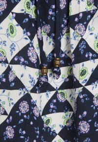 Navyblauwe gestreepte stof met bloemen- en geometrische ontwerpen, voorzien van verstelbare trekkoorden en met handelsaccenten van messing.