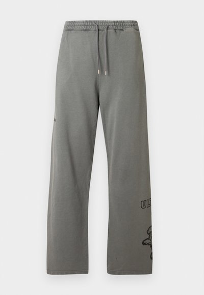 Pantalon de survêtement gris à coupe décontractée, doté d'une taille élastique, d'un cordon de serrage et de motifs imprimés sur la partie inférieure de la jambe. Matière douce en coton.