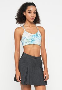 Sportos, világoskék és zöld virágmintás crop top, amelyet egy sötétszürke, pliszírozott szoknyával párosítottak, amelynek derékon gombos záródása van.
