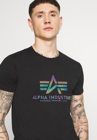 T-shirt in cotone nero con logo grafico multicolore raffigurante una "A" e ali, colletto a coste e maniche corte.