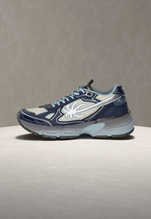 Blauer und grauer Sportschuh mit weißem Flammendesign an der Seite, hellblauen Schnürsenkeln und dicker, strukturierter Sohle auf neutraler Oberfläche und Hintergrund.