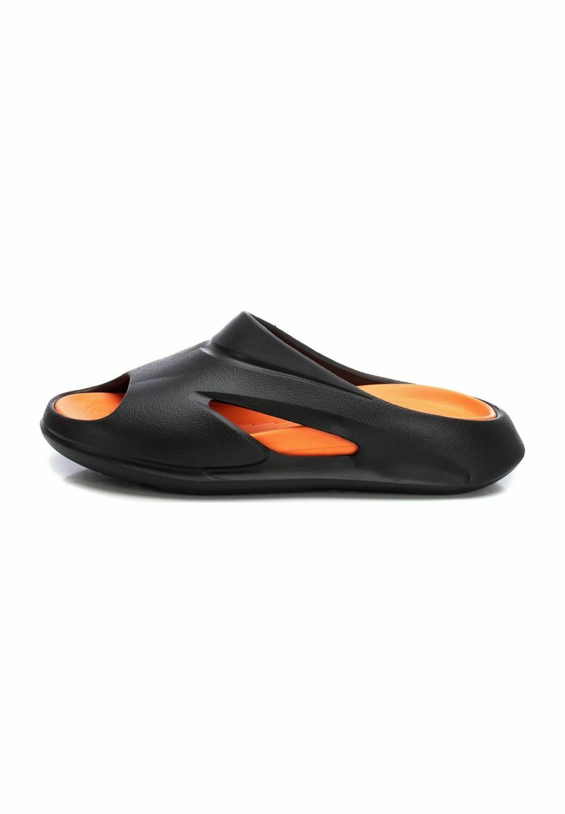 Calzado negro con un diseño abierto, que presenta secciones recortadas. El interior es naranja, fabricado con un material moldeado de textura suave.