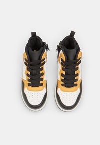 Hoge sneakers met een zwart, wit en oranje kleurenpalet, lederen materiaal, geperforeerde neus, en zwarte veters met ritsen.