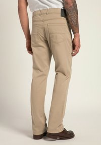 Pantalones de algodón beige con corte recto, que cuentan con dos bolsillos traseros, costuras visibles y una etiqueta negra en la cinturilla.