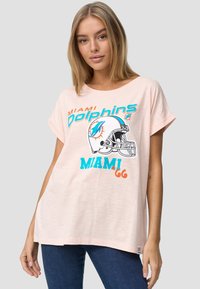 Lys pink, løs t-shirt med korte ærmer. Har et Miami Dolphins grafisk design i teal, orange og sort med hjelm og slogan.