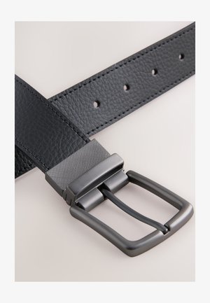 Svart läderbälte med ett texturerat spänne i mörkt metall; har flera hål för justering och en slät yta på remmen.