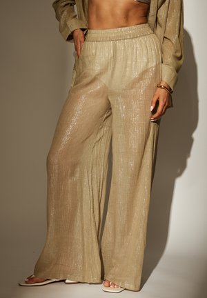 Pantalons larges en beige transparent avec une finition texturée et un subtil éclat, dotés d'une taille élastique et d'une silhouette fluide.