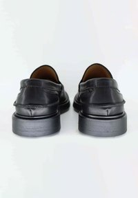 Scarpe in pelle nera con finitura liscia, punta rotonda e suola bassa in gomma nera. Presentano delle cuciture sottili e un design pulito.