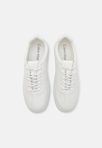 Valged nahast espadrillid ümarate varvaste, tekstureeritud disaini ja korterite valgete paeltega. Brändimine siseriidetes ja minimalistik stiil.