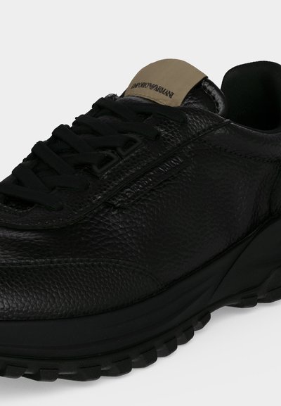 Μαύρο sneaker από δερματίνη με μαύρα κορδόνια και μπεζ ετικέτα στη γλώσσα με το λογότυπο Emporio Armani.