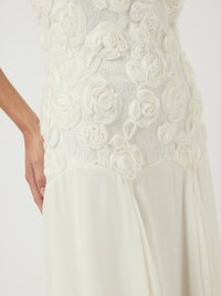 Λευκό φόρεμα με ραφές από υφή λουλουδιών στο μπούστο, διάφανη υφή που κρέμεται από τη μέση; λείο φινίρισμα και μαλακή εμφάνιση.