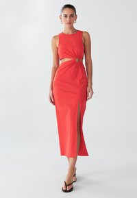 Crvena, haljina bez rukava srednje dužine s izrezom u struku koji ima okrugli ukras. Glatka tkanina sa bočnim prorezom i jednostavnim krojem.